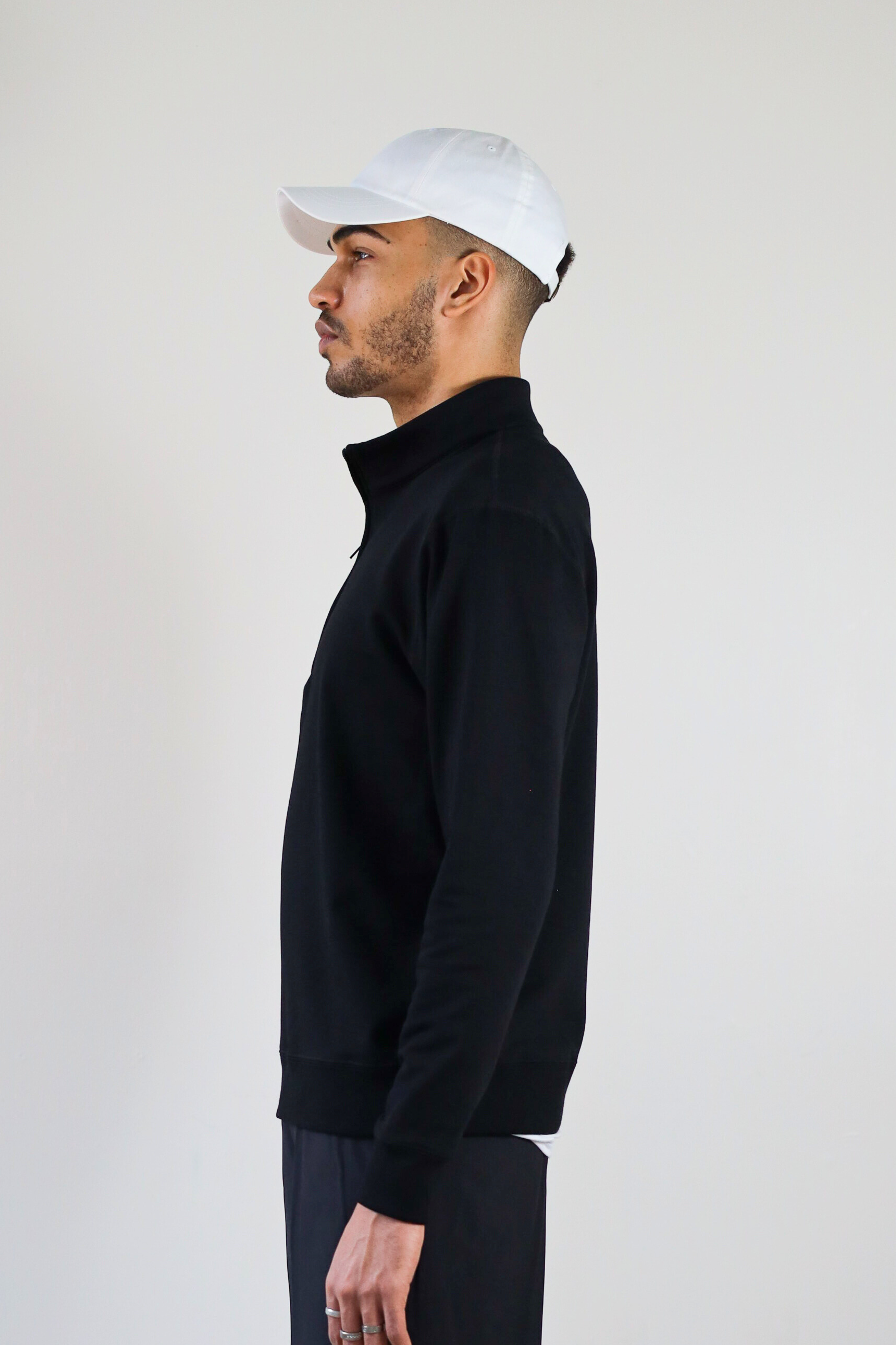 Men’s 1/4 Zip Crewneck in Black – side profile on model showing sleeve shape, collar height, and relaxed structure