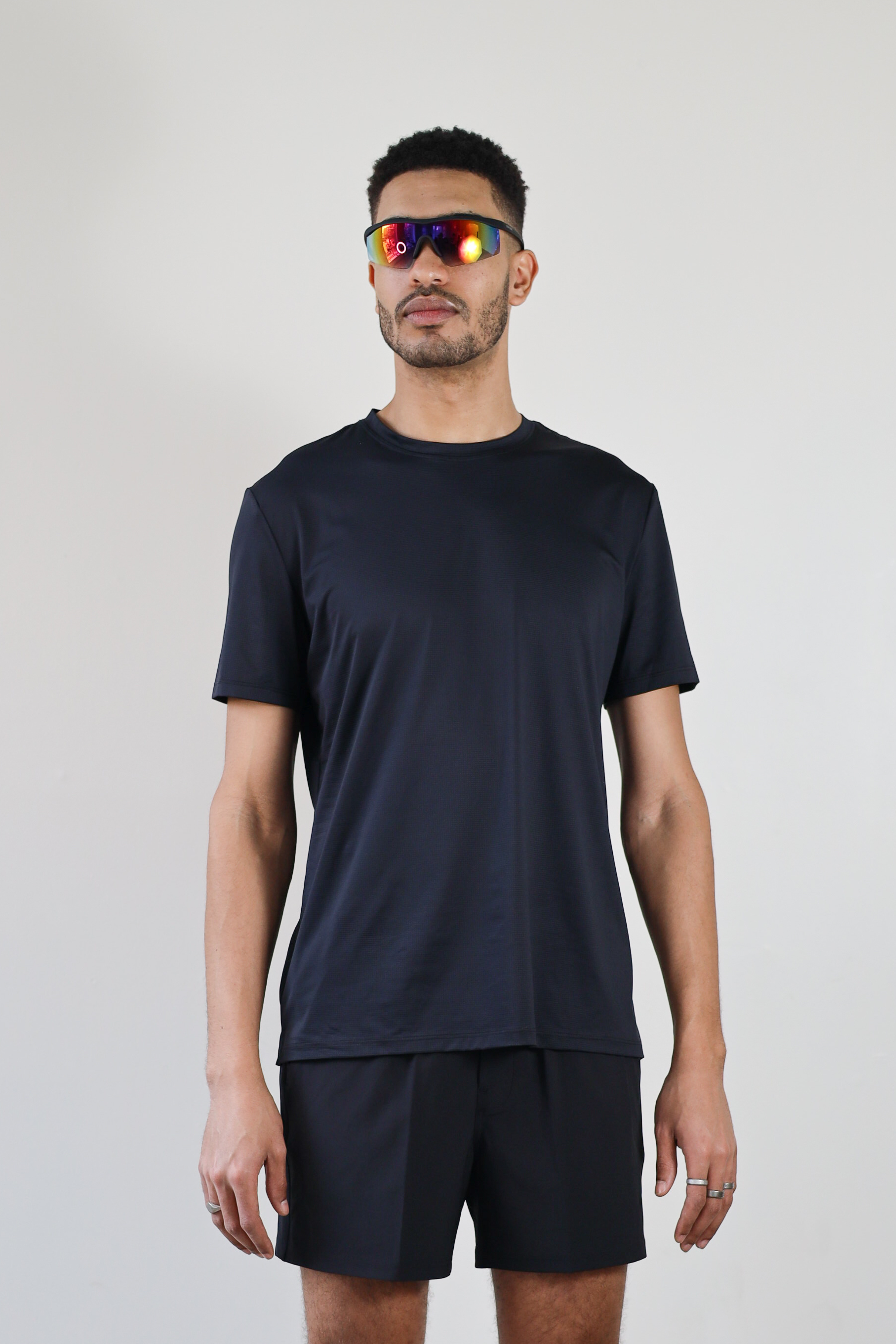 A model wearing the Unisex Short Sleeve Runners Tee in black, standing front-facing to showcase the sleek, athletic fit and lightweight, moisture-wicking fabric for all-day performance.