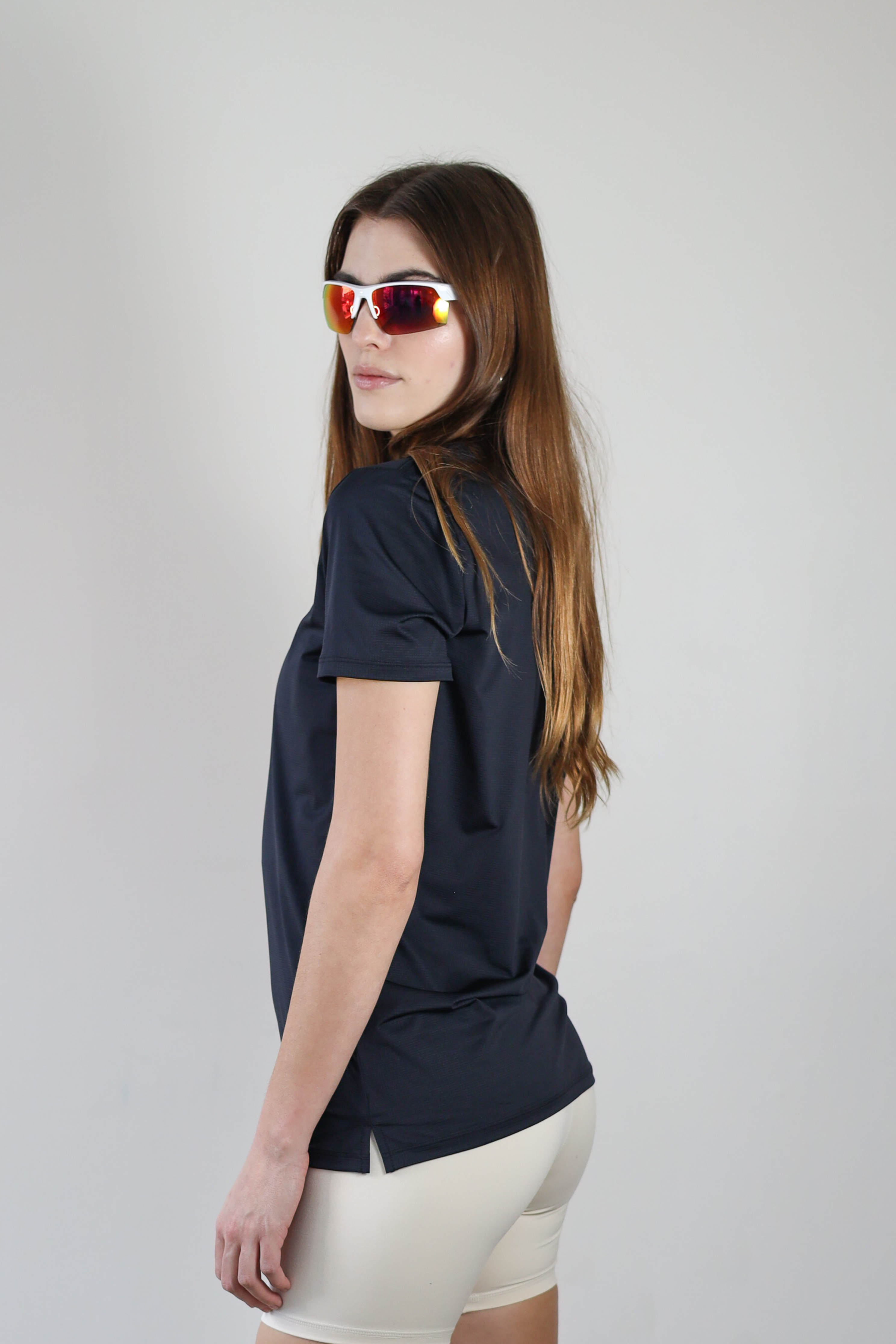 A side view of a model wearing the black Unisex Short Sleeve Runners Tee, emphasizing the ventilated mesh fabric, ergonomic fit, and stretch for unrestricted movement.