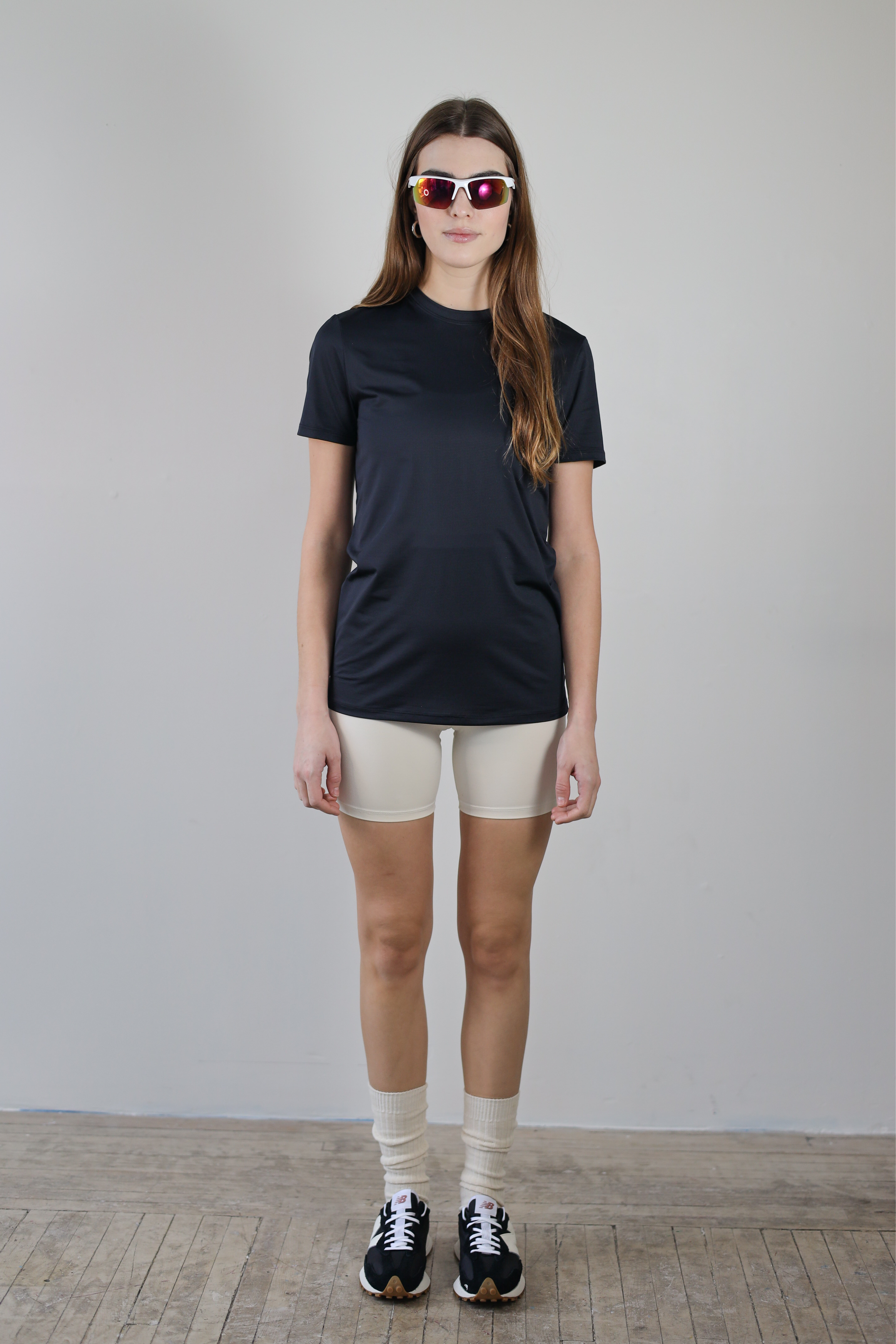 A full-body shot of a model wearing the Unisex Short Sleeve Runners Tee in black, standing front-facing, highlighting its versatile design, breathable fabric, and functional fit for running, training, and everyday wear.